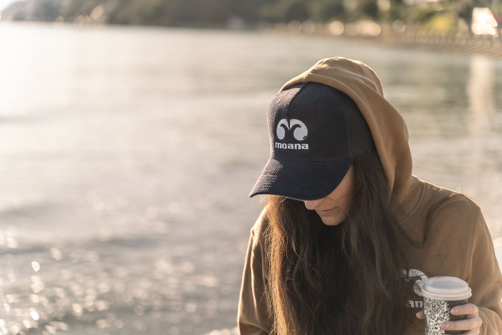 Women on the beach with a coffee wearing a Moana OG Cord Trucker Cap